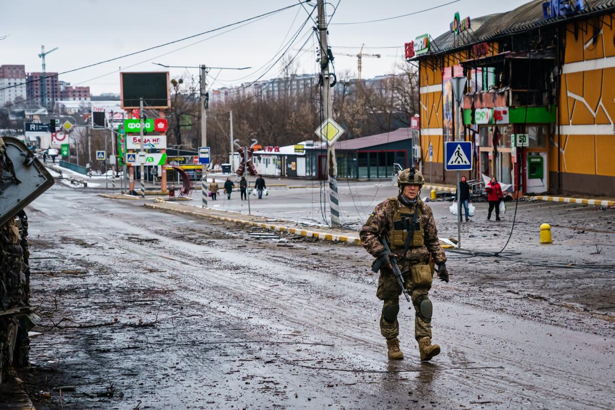  A Ukrainian soldier walks past a building that was destroyed