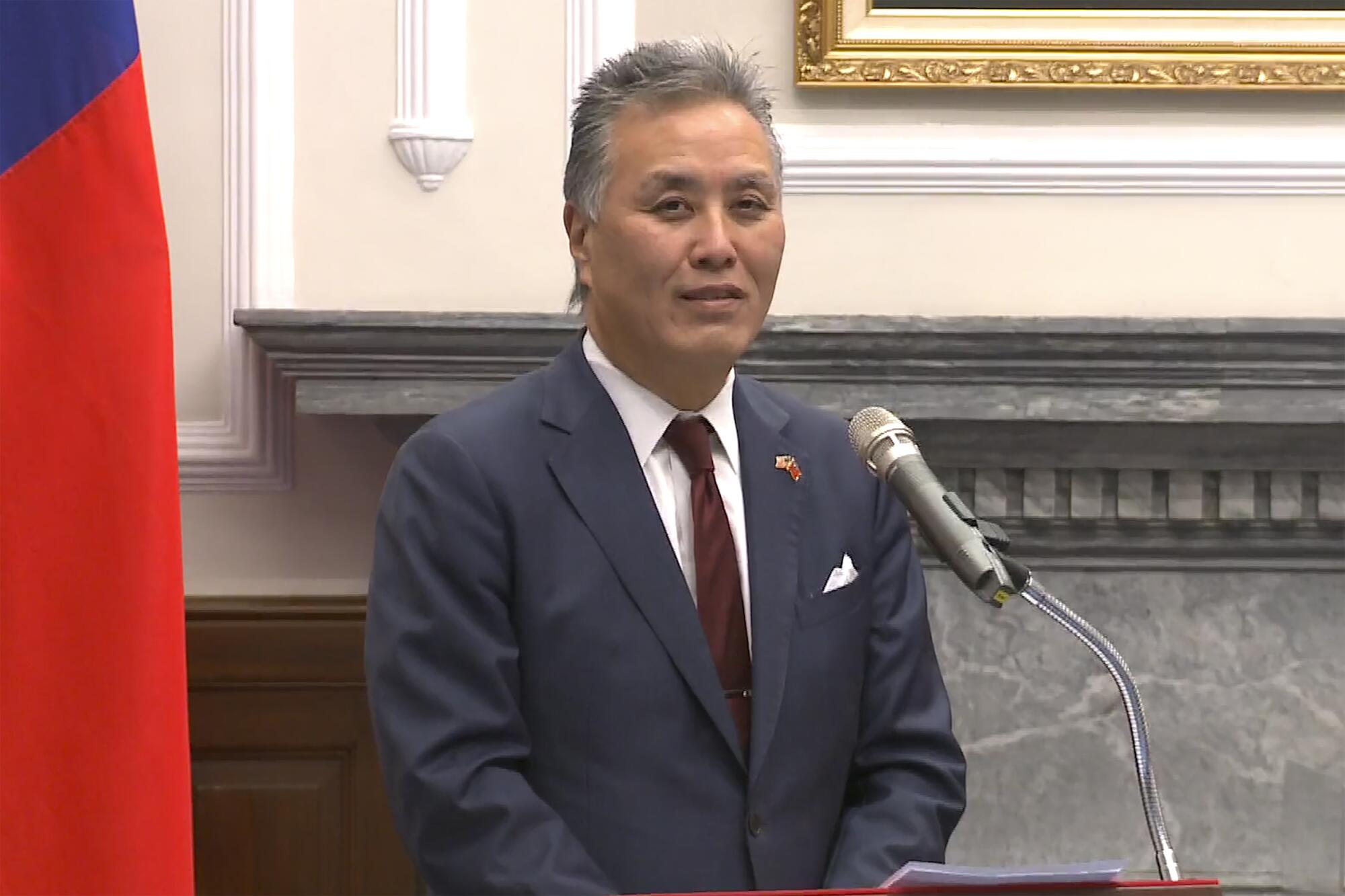 El representante Mark Takano parado frente a un micrófono