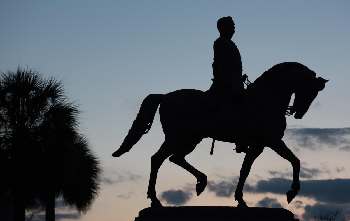 A silhouette of a person on a horse seen against a dusky sky.