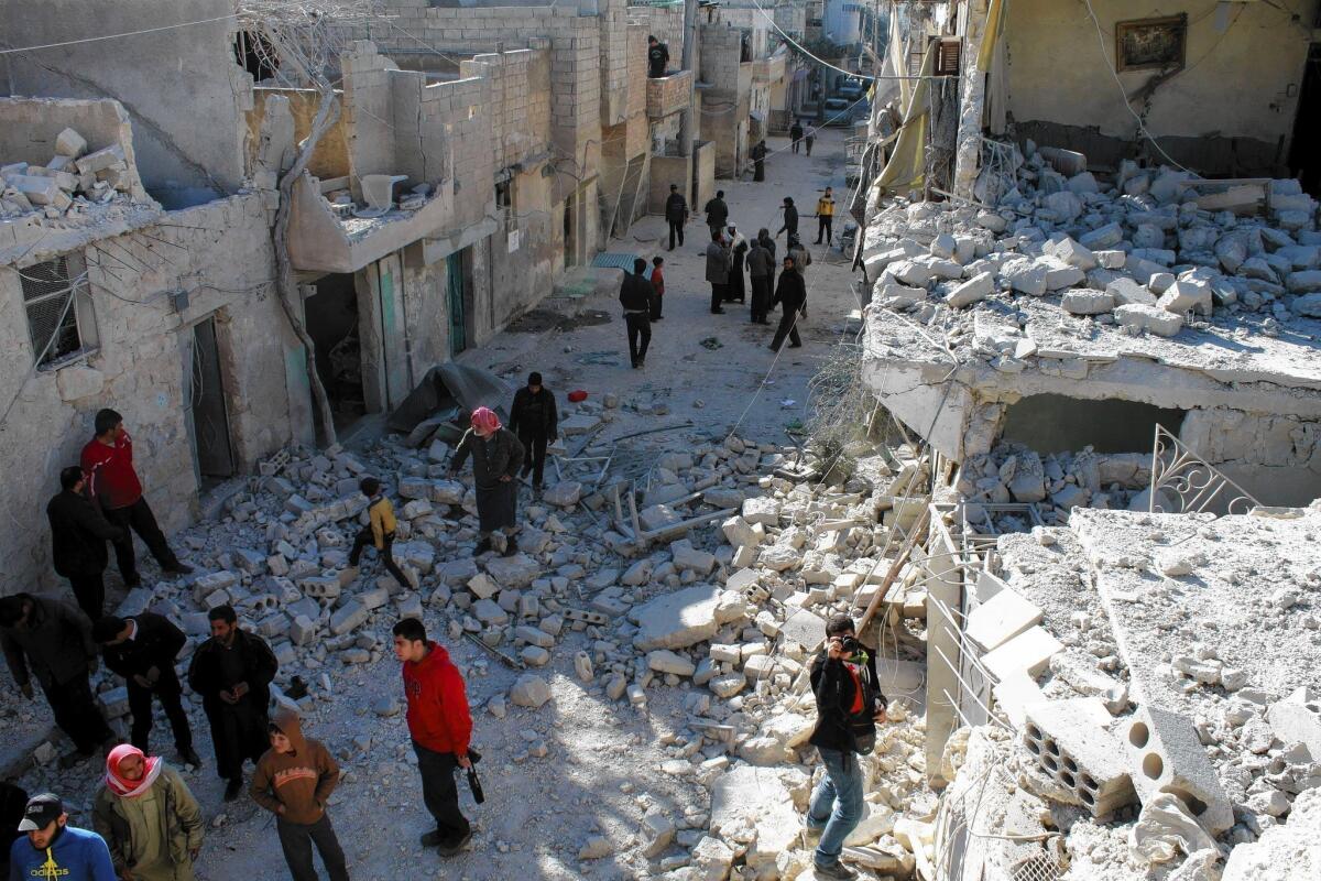Syrians walk through a street reduced to rubble by an airstrike in Aleppo, where the government has been dropping TNT-filled oil drums.