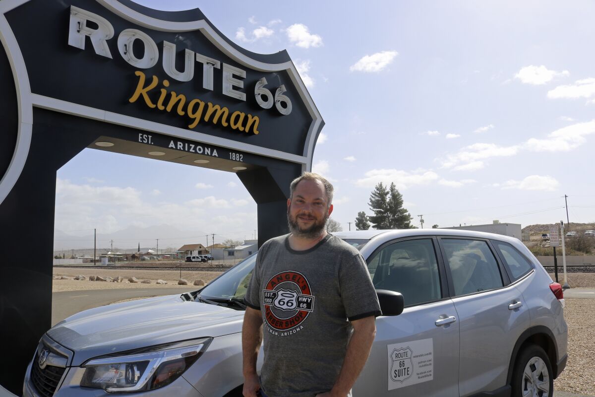 Music professor and composer Nolan Stolz poses beside the Route 66 Kingman sign outside the Powerhouse Visitors Center in Kingman, Ariz., Feb. 18, 2022. He's traveling the length of the route from end-to-end and back again and again seeking inspiration for his Route 66 Suite composition for symphony orchestras, to be performed in the 2025-26 season to celebrate the highway’s 2026 centennial, will contain eight movements, and be titled “Route 66 Suite.” (Travis Rains/Kingman Daily Miner via AP)