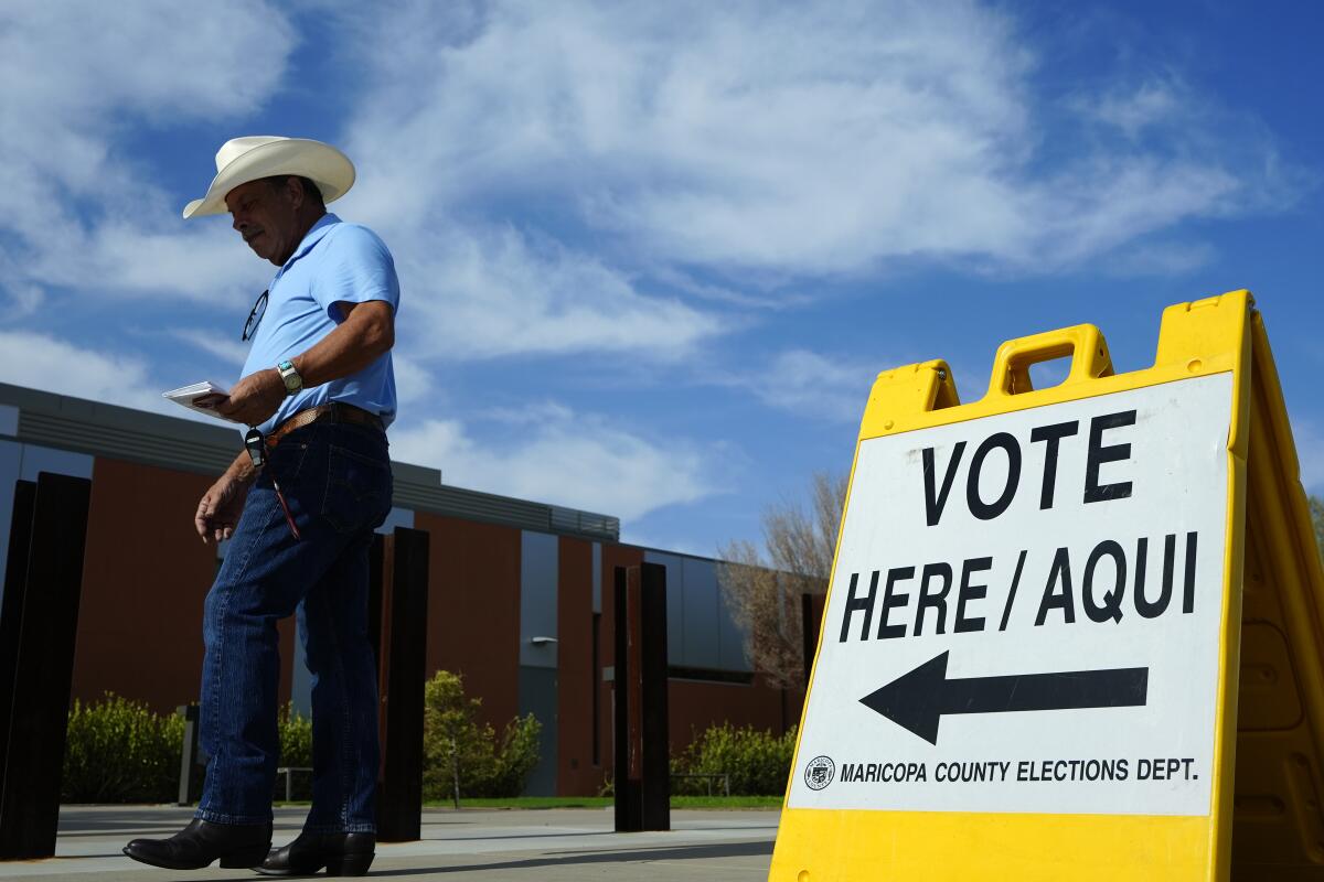 A man next to a sign that says "Vote Here / Aqui"