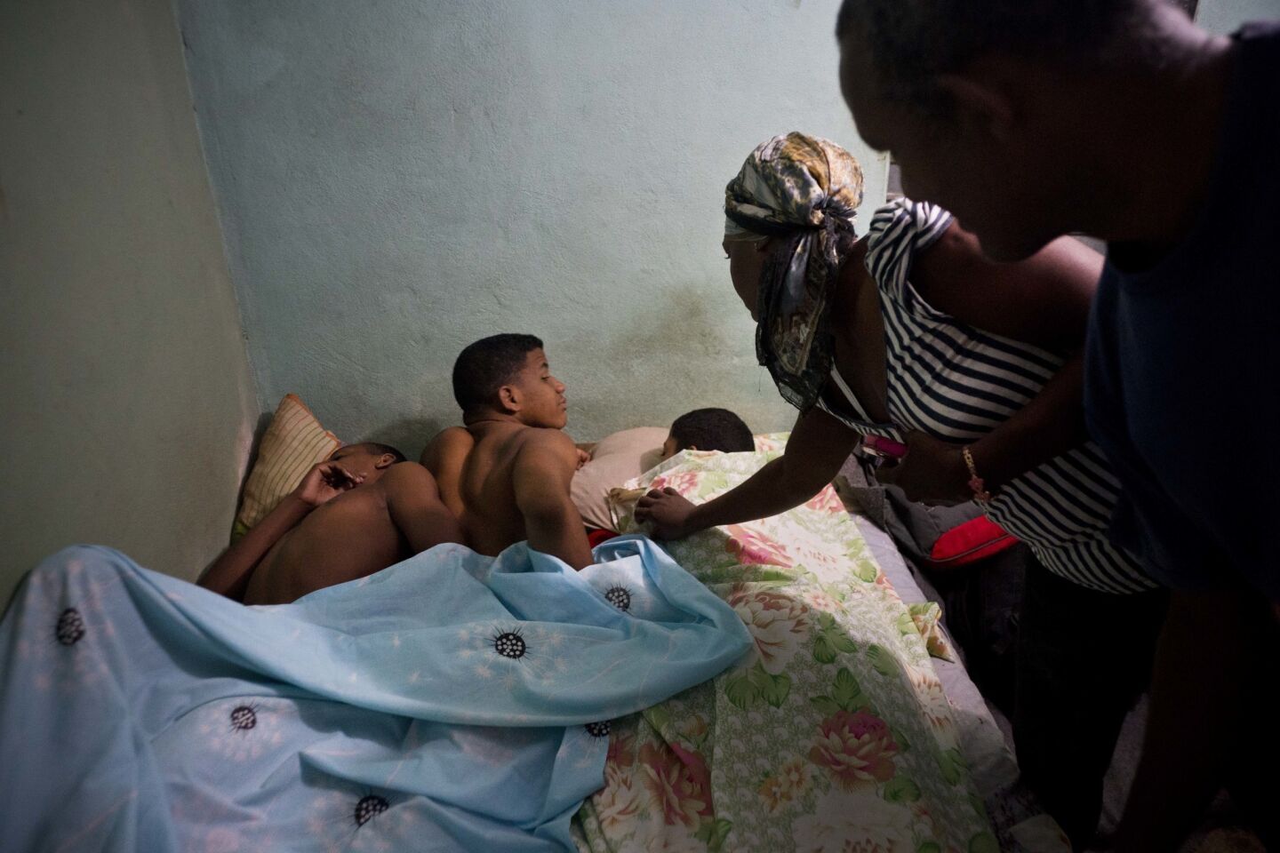 La pareja formada por Leandro Heredia Marrero (d) y su esposa Leticia despiertan a tres jóvenes luchadores que se alojan en su casa para un torneo amateur organizado por vecinos del vecindario de Chicharrones, en Santiago, Cuba.