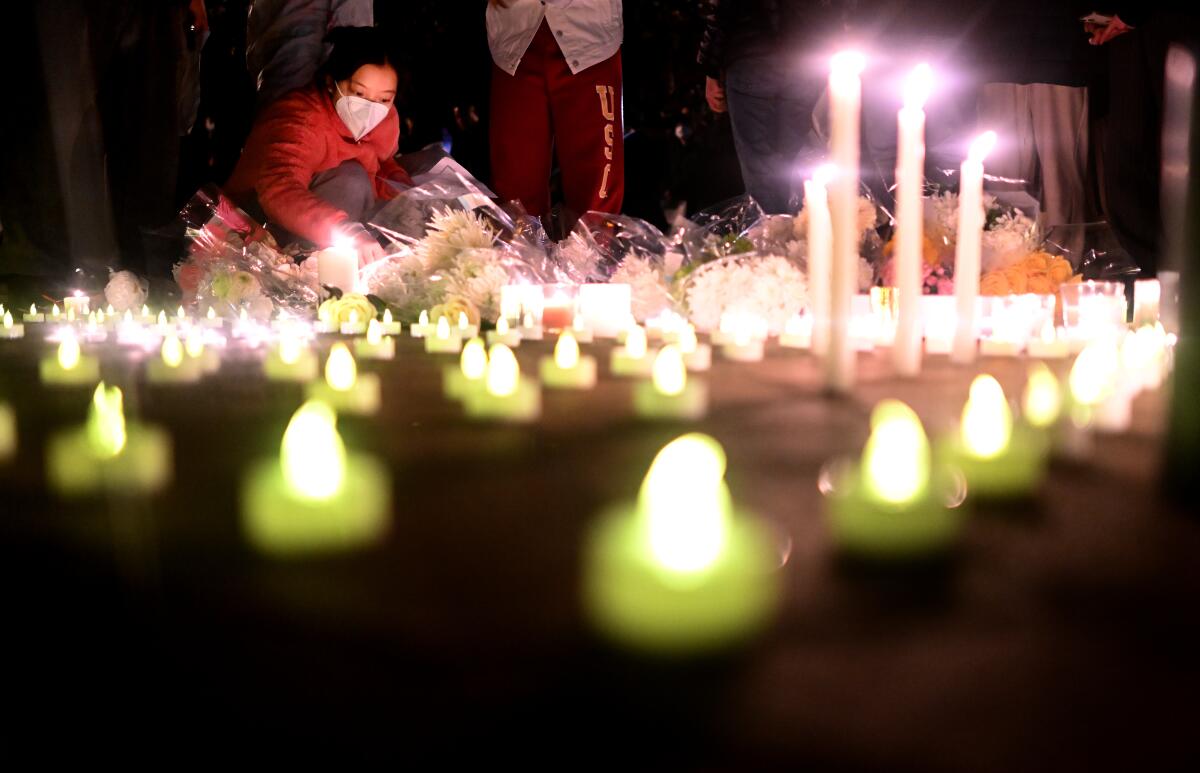 A woman lights a candle during a vigil for victims who suffer under China’s stringent lockdown