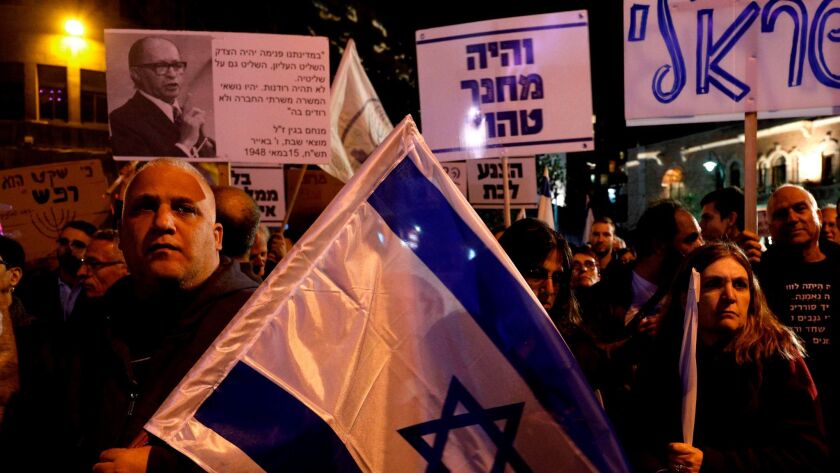 In Jerusalem, Israelis protesting at a right-wing demonstration against corruption hold placards reading in Hebrew, "And our camp was pure" and "I am Israeli."