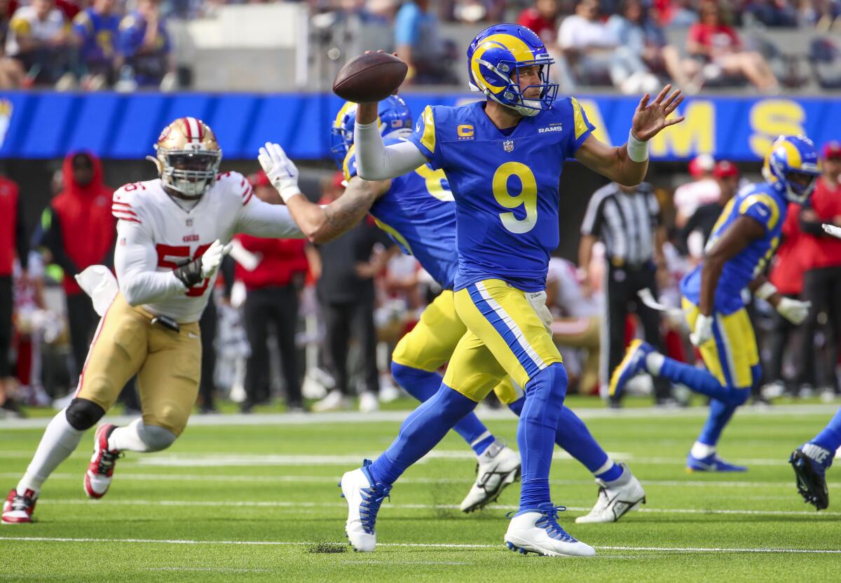 Rams quarterback Matthew Stafford throws on the run under pressure from the 49ers defense.