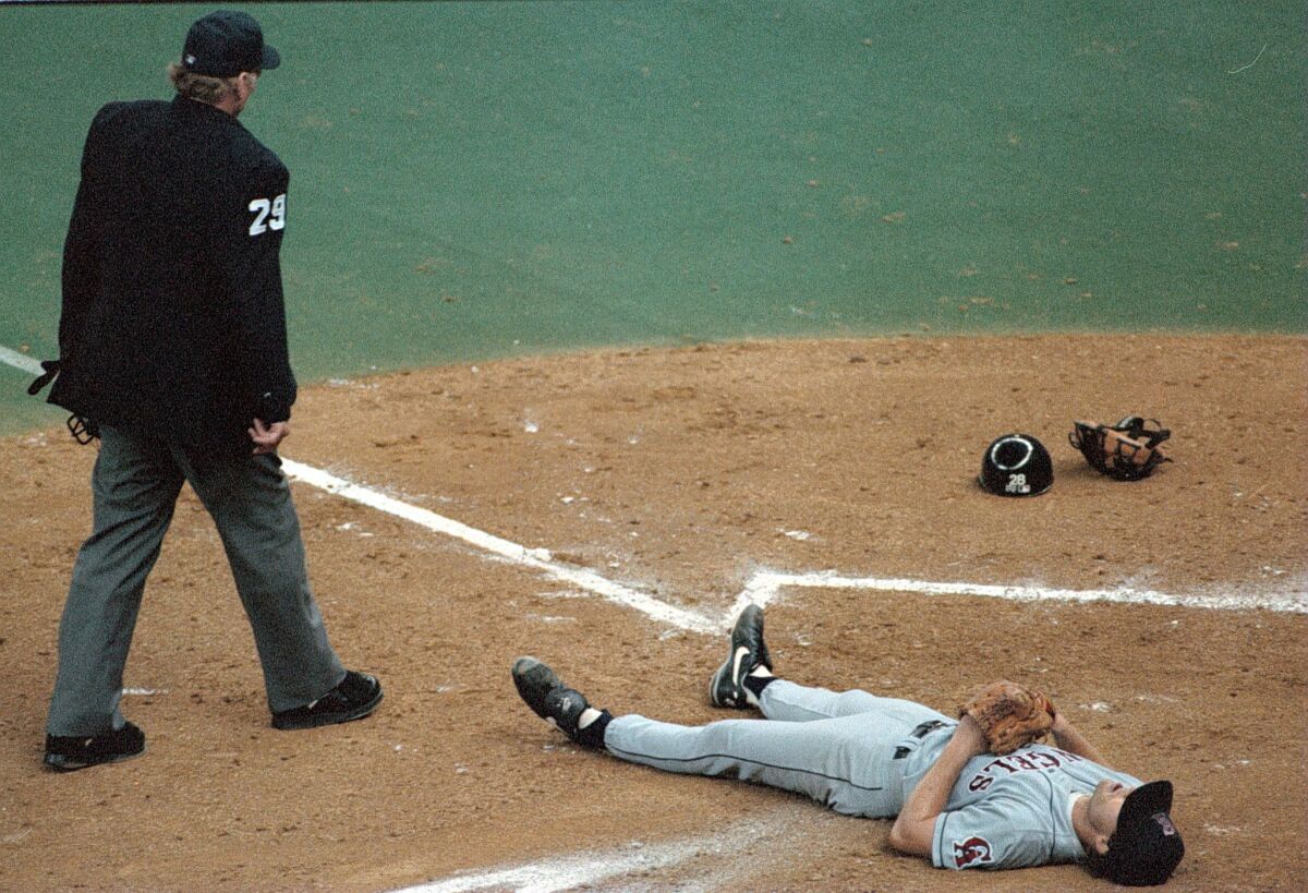 Angels pitcher Mark Langston lies dejected by the umpire at home plate after Mariners infielder Luis Sojo scored on a broken bat double with the bases loaded.