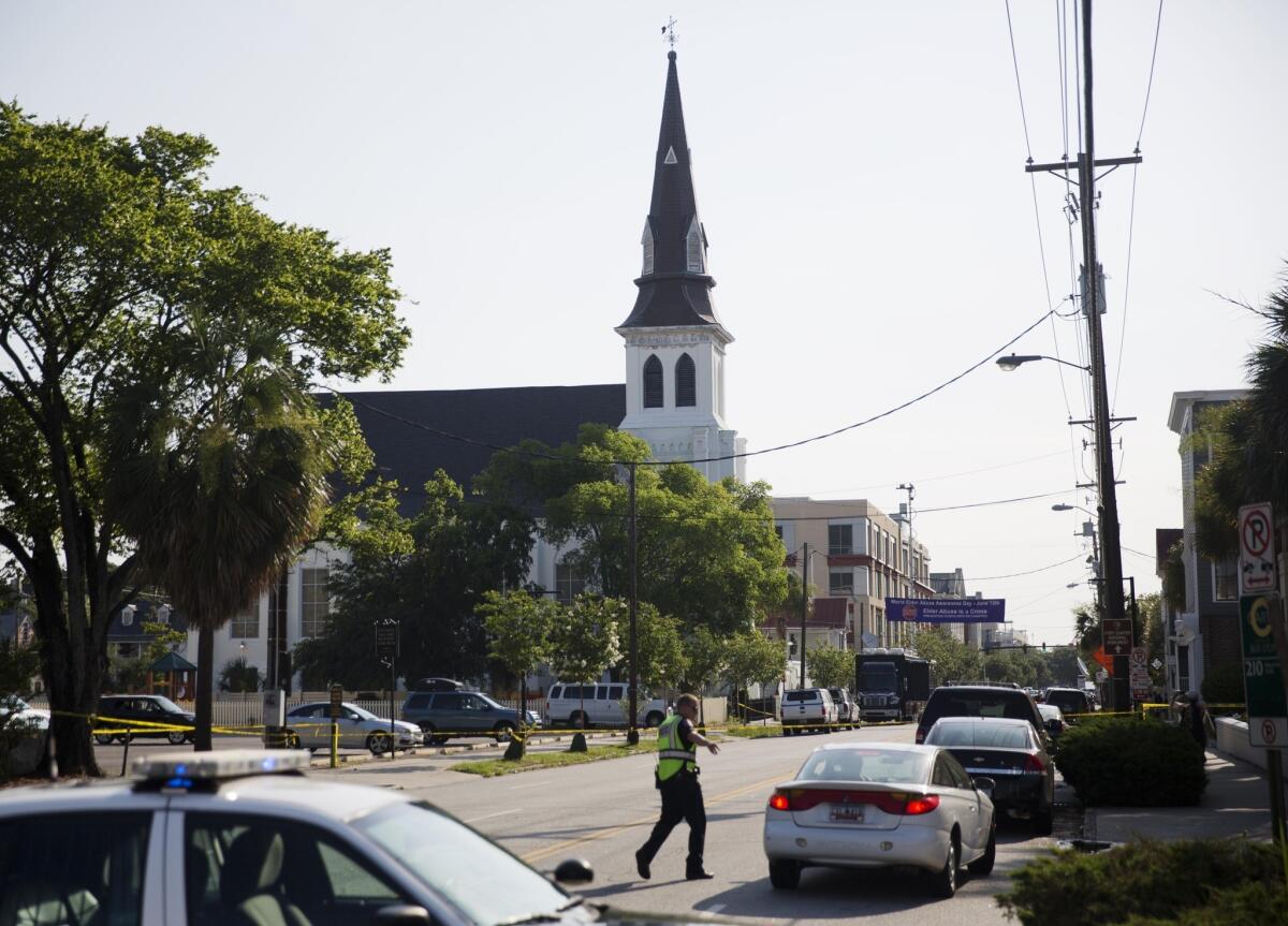 The steeple of Emanuel AME Church in Charleston, S.C., rises above the street as a police officer tells a car to move as the area is closed off after June's deadly shooting.