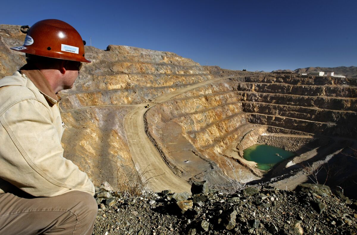 A miner wearing a helmet peers into a rare earth mineral mine in Mountain Pass, Calif.