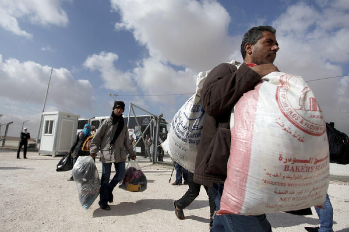 Syrians carry their belongings as they arrive at the Mrajeeb Fhood refugee camp in Zarqa, Jordan