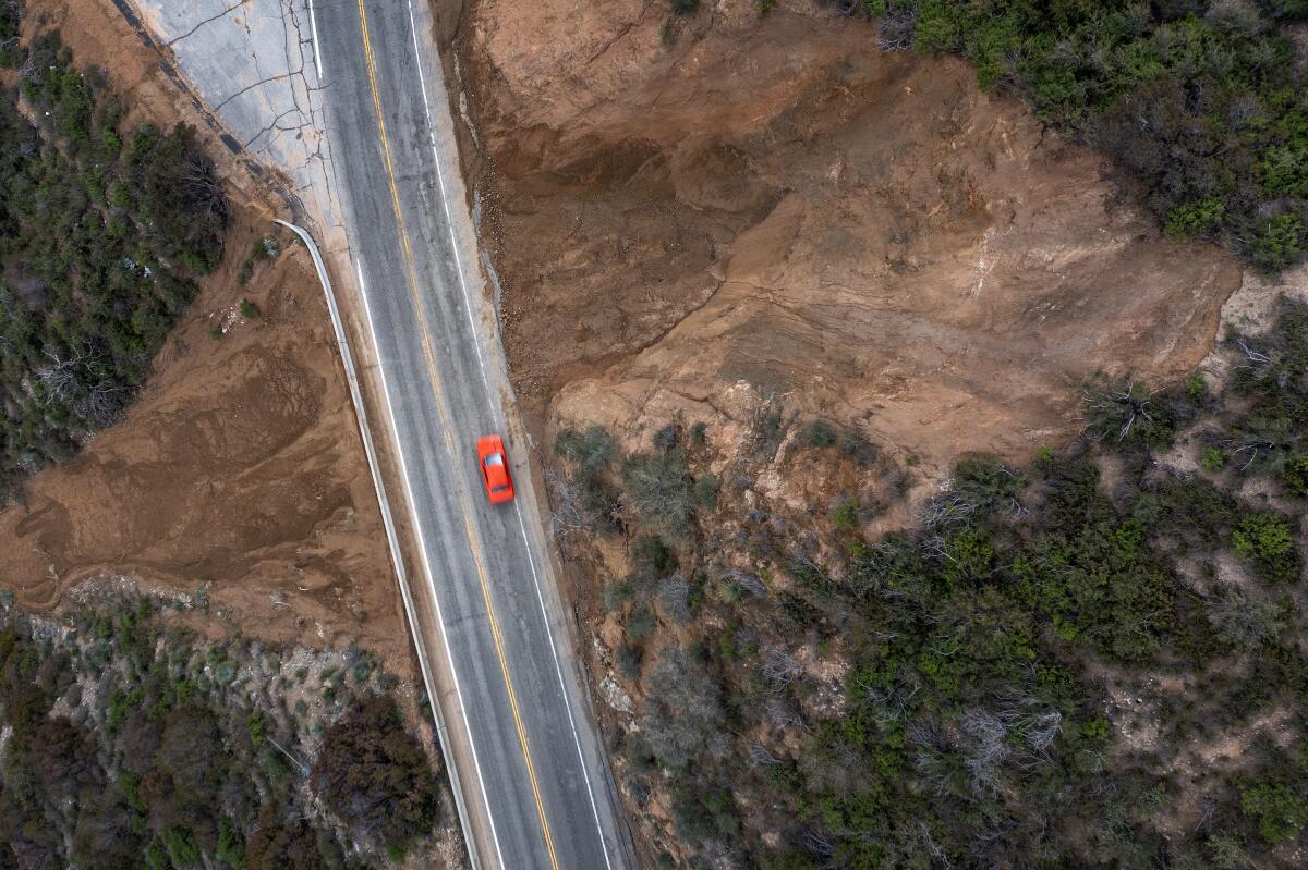 A red vehicle, seen from above, on a hillside highway