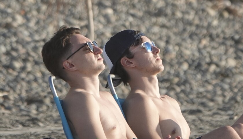 dos jovenes se asolean en la playa