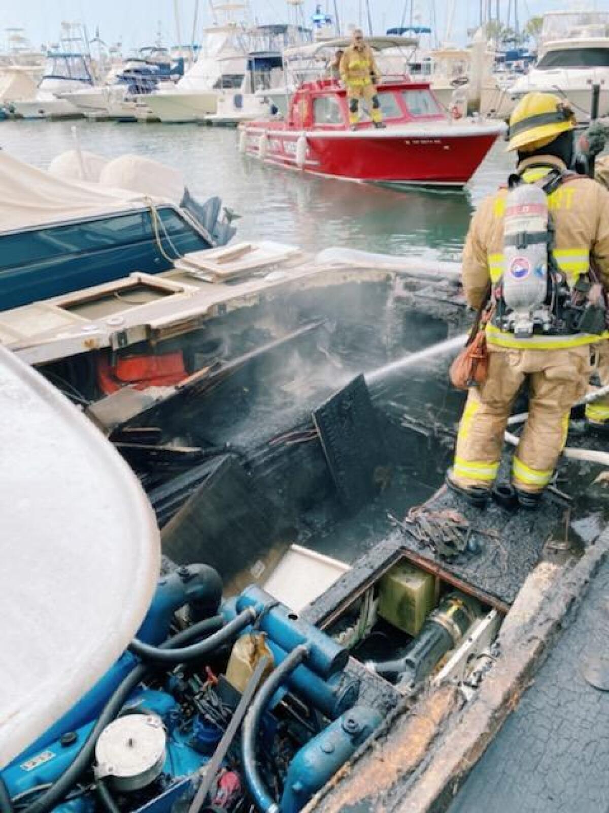 A firefighter stands in the wreckage of one of the boats damaged in a fire at the Balboa Yacht Basin.