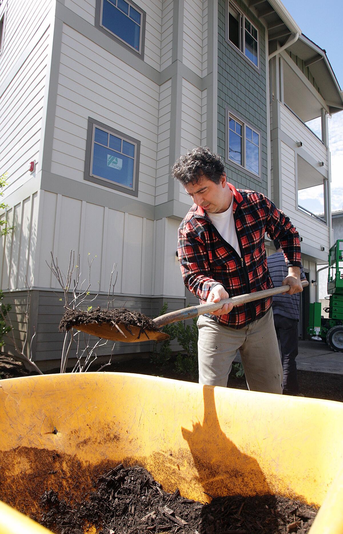 Henrik Sarkisyan, of Glendale, scoops mulch to spread onto the landscaped grounds in front of Chestnut Homes, the newest project near completion by Habitat for Humanity, on Friday, March 11, 2016. The project broke ground in July, 2014, and a lot of preparation is being done all over the property to prepare for a dedication ceremony on Saturday.