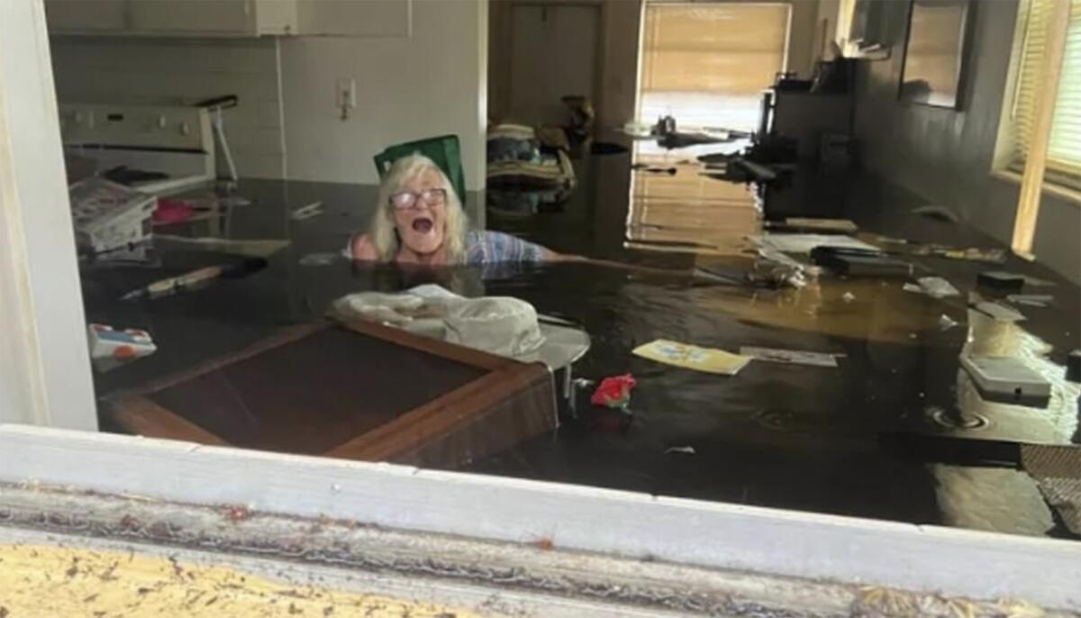 An 86-year-old woman is submerged nearly to her shoulders in water that has flooded her home.