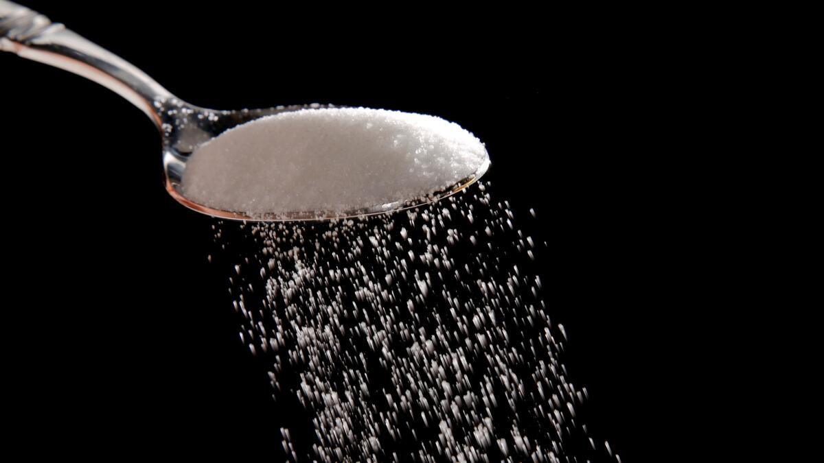 Sugar being sprinkled from a spoon.