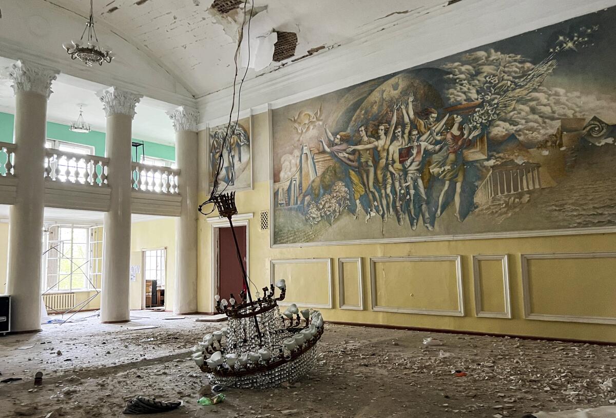 A fallen chandelier sits on the floor of a damaged ballroom.