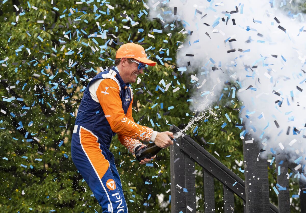 Scott Dixon, of New Zealand, celebrates with champagne in the Winners Circle after winning an IndyCar auto race in Toronto, Sunday, July 17, 2022. (Mark Blinch/The Canadian Press via AP)