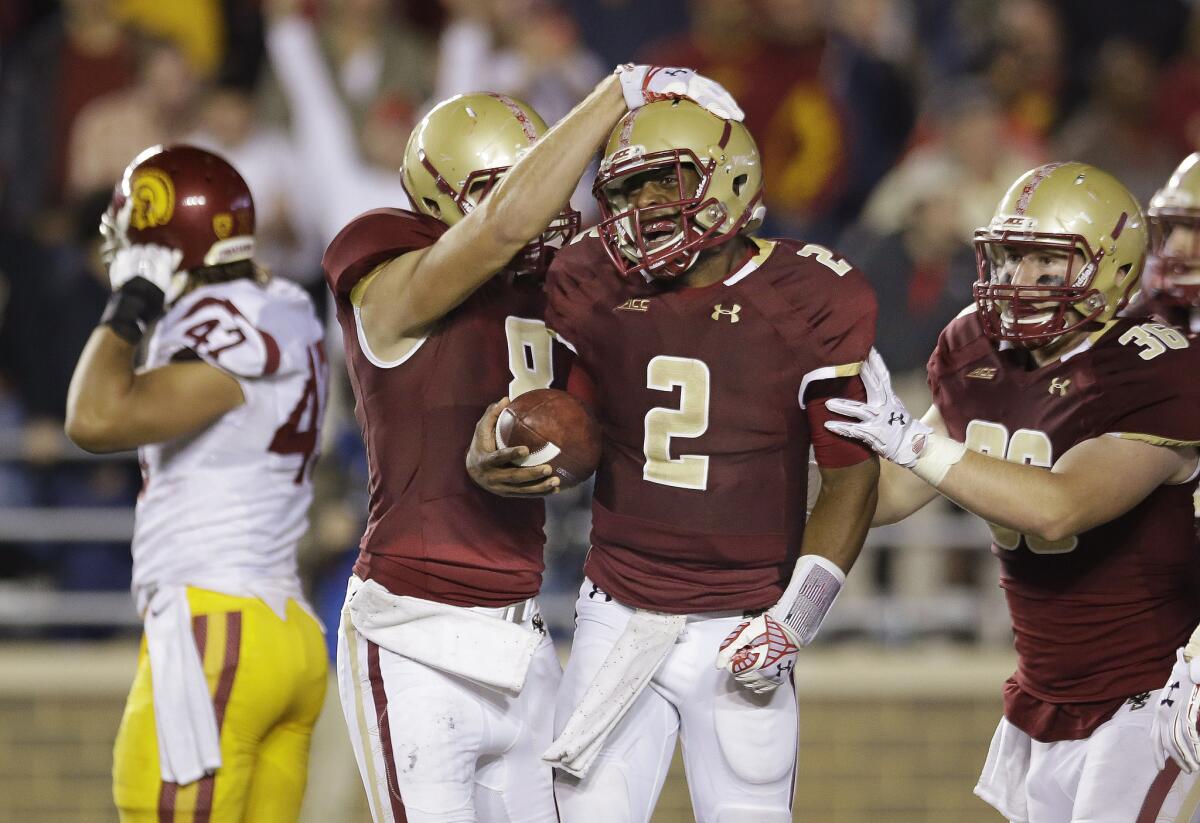 Boston College quarterback Tyler Murphy celebrates with wide receiver Josh Bordner and fullback Bobby Wolford as USC linebacker Scott Felix walks off the field after the Trojans' 37-31 loss to the Eagles on Sept. 13.