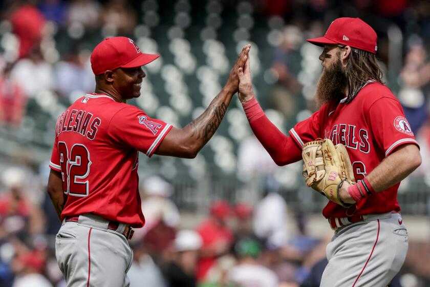 Los Angeles Angels relief pitcher Raisel Iglesias (32) celebrates with teammate Brandon Marsh.