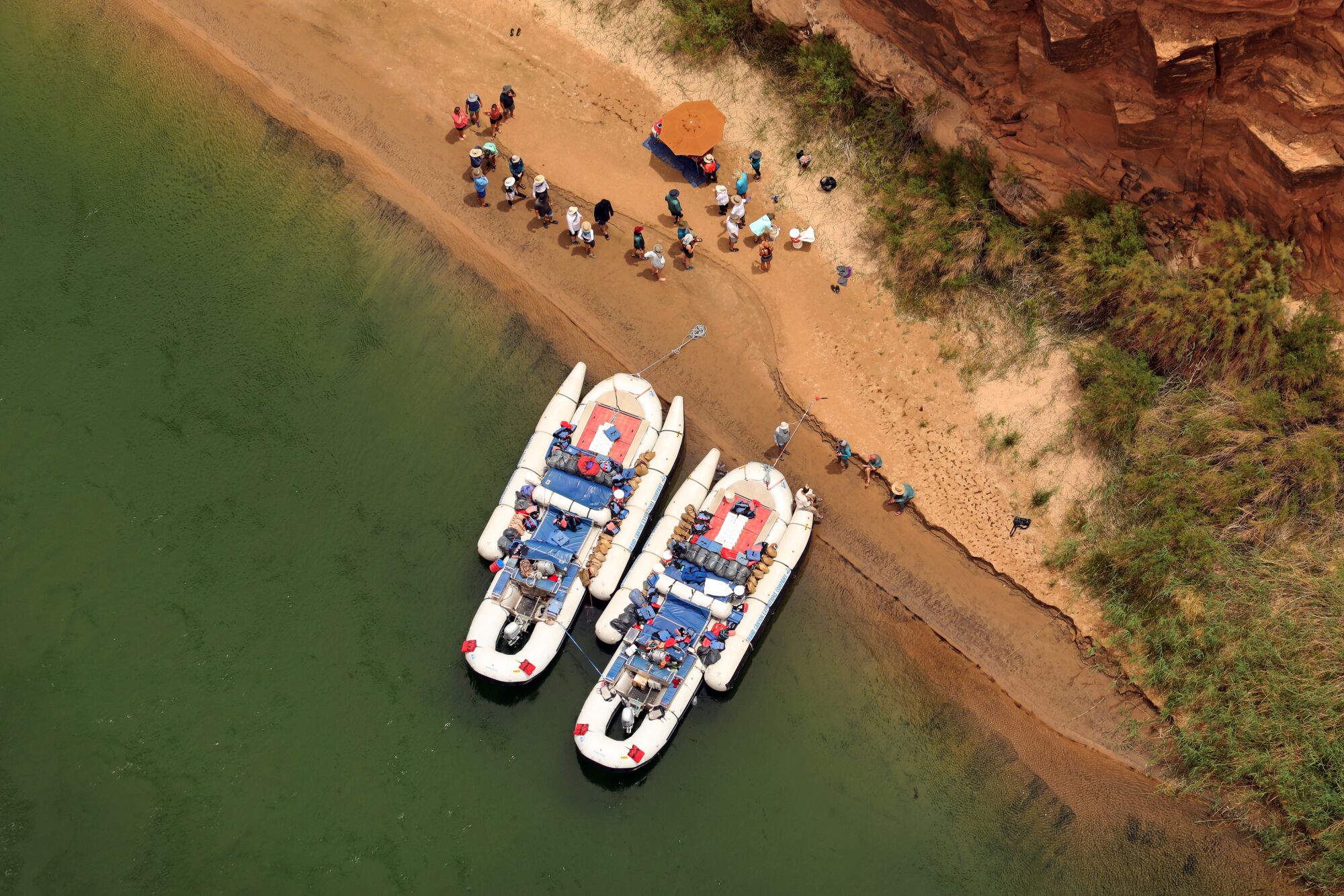 Aerial view of two rafts in a river with people on the shore