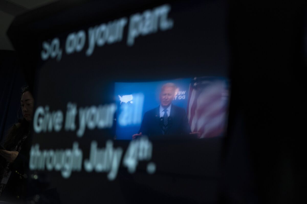 President Biden is reflected in a teleprompter.