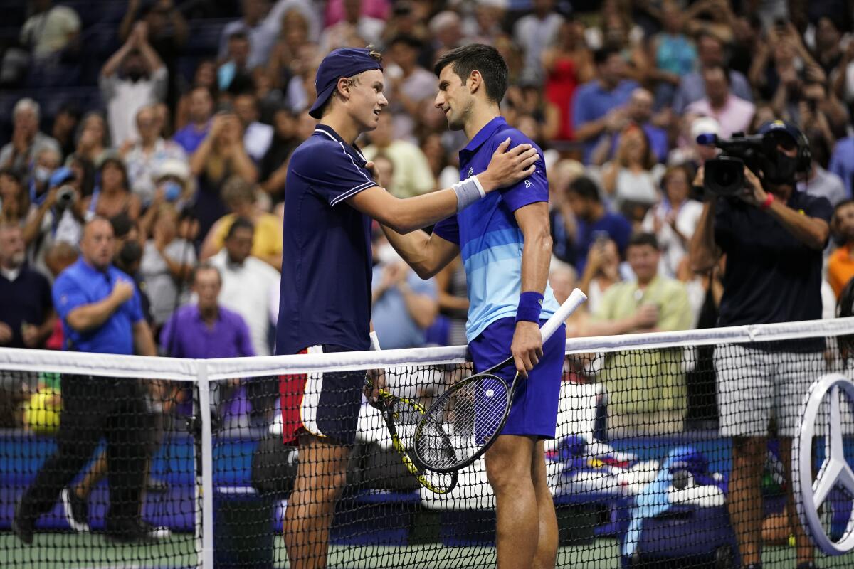 Holger Vitus Nodskov Rune and Novak Djokovic meet at the net.