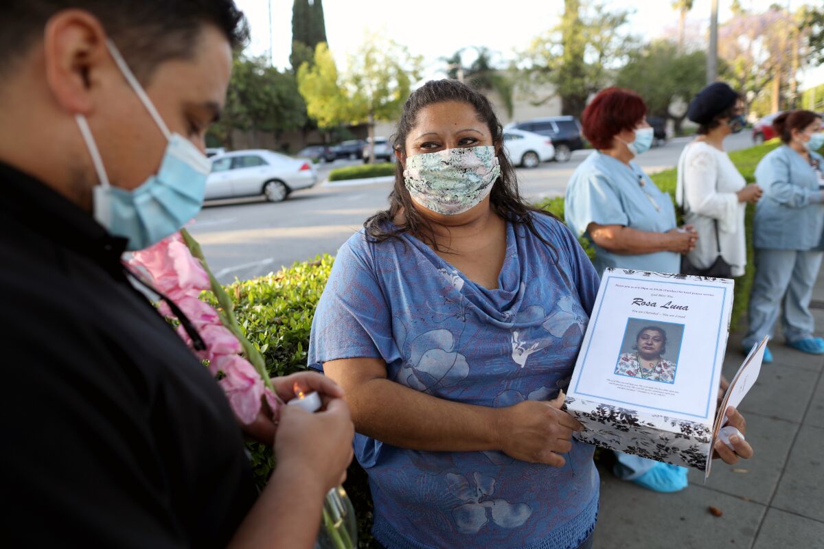 Dora Reaza holds a photo of her mother, Rosa Luna, during a vigil at Riverside Community Hospital. 