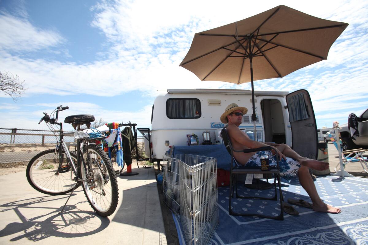 Mike Anderson of Covina relaxes under an umbrella next to his Casita at Bolsa Chica State Beach in Huntington Beach.