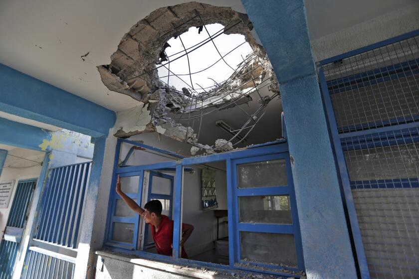 A boy staying at a U.N. shelter in Jabaliya waves to a friend. Earlier, the shelter was shelled; 16 people were killed.