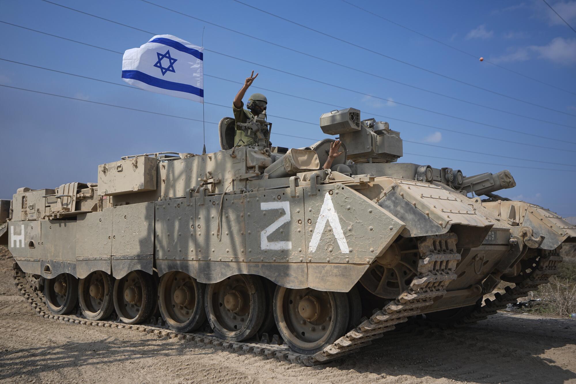 Israeli soldier flashing V-sign from an armored personnel carrier heading toward Gaza