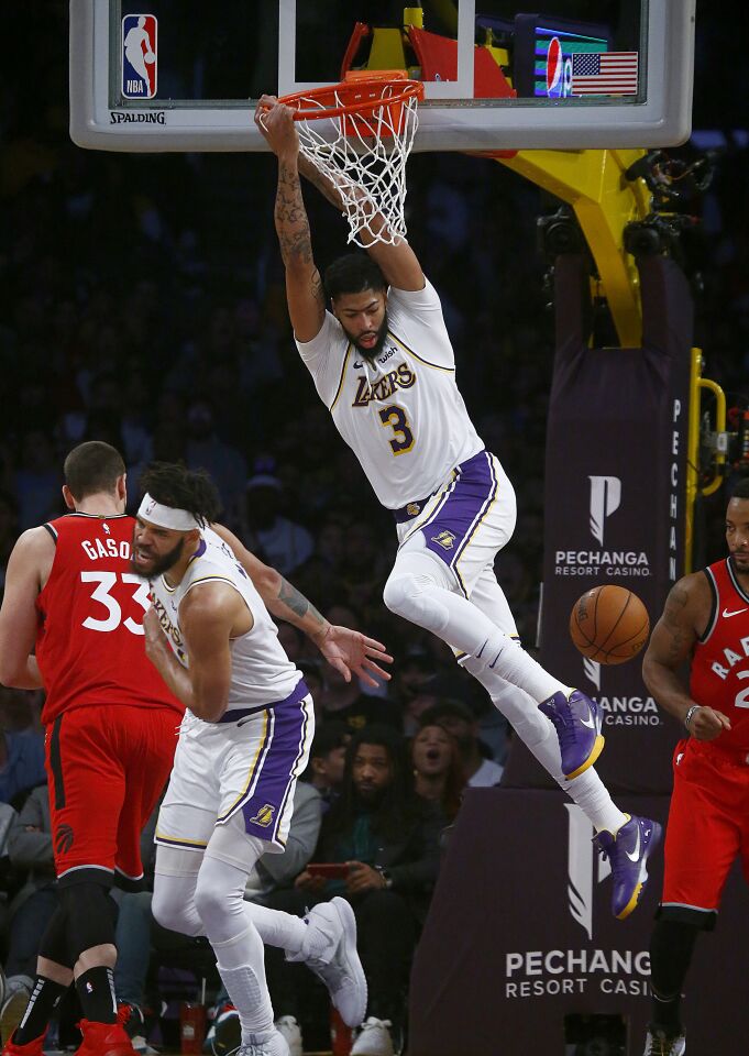 Lakers forward Anthony Davis hangs on the rim for a moment after dunking against Toronto during the third quarter.