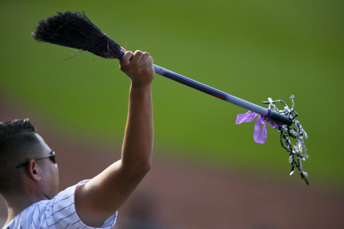 A Rockies fan holds up a broom as Colorado swept the Dodgers on Sunday.