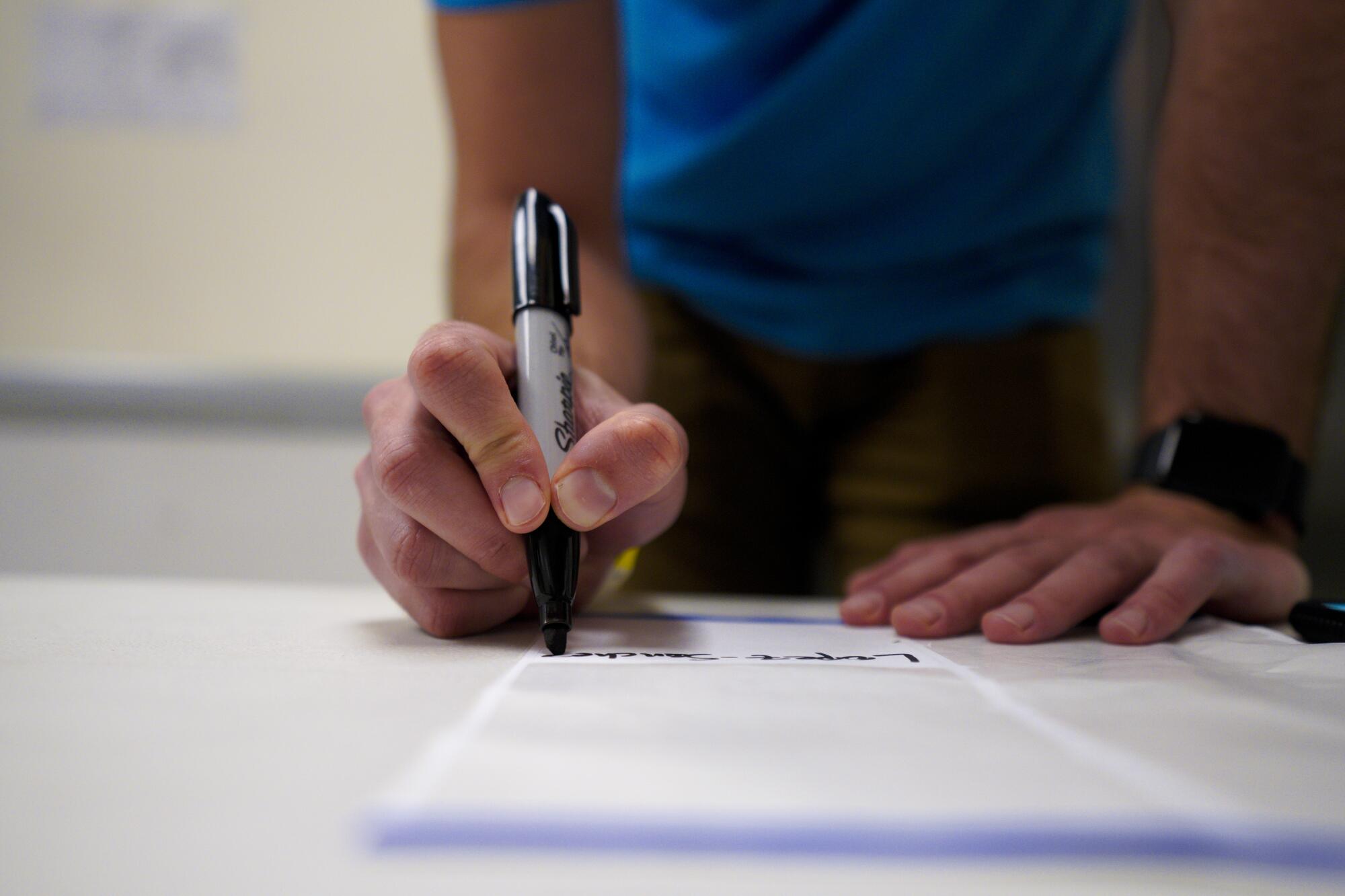 A detailed view of a hand writing with a Sharpie