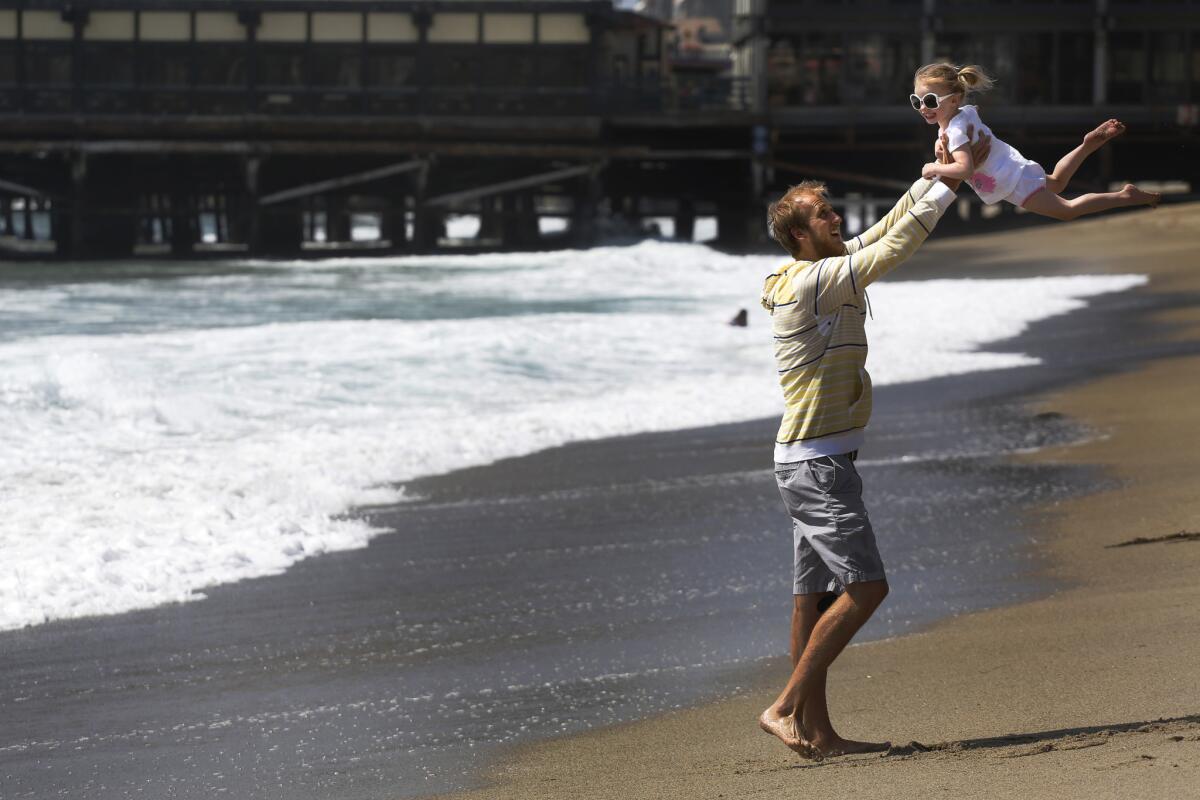 Lance Johnson of Albuquerque, N.M., swings his niece Elsa Schulte, 3, just south of the Redondo Beach pier. The beach got an F for the winter months and a C for summer in Heal the Bay's annual report card.