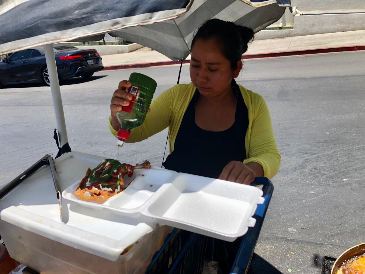 María García le agrega salsa picante al pollo y papas fritas que sirve a un cliente en la avenida Bonnie Brae.