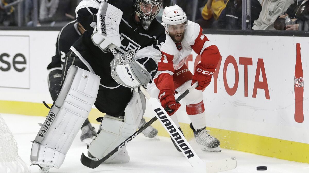 Kings goaltender Jack Campbell, left, clears the puck as Detroit Red Wings' Luke Glendening, right, closes in during the first period on Sunday