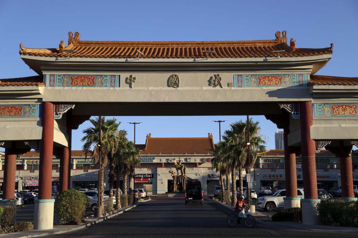 A man rides his bike under a Chinese-style archway into a shopping center.