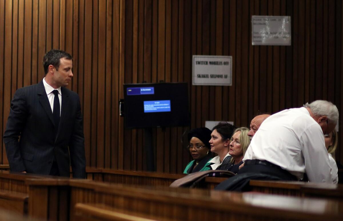 South African athlete Oscar Pistorius, left, looks at June Steenkamp, third from left, and Barry Steenkamp, the parents of Reeva Steenkamp, whom Pistorius shot and killed last year.