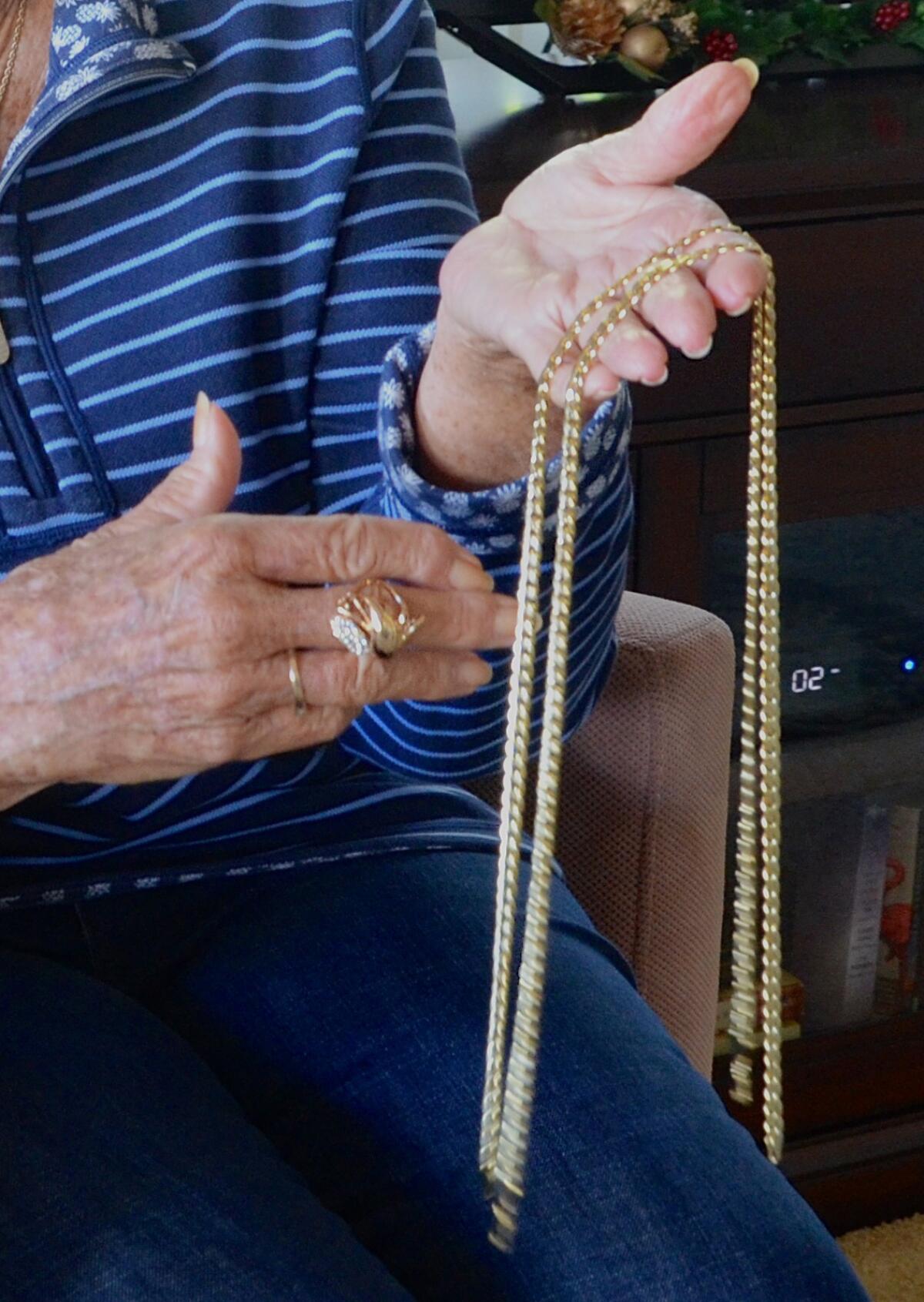 A victim of jewelry swap scam holds counterfeit necklaces and ring given to her by a thief.