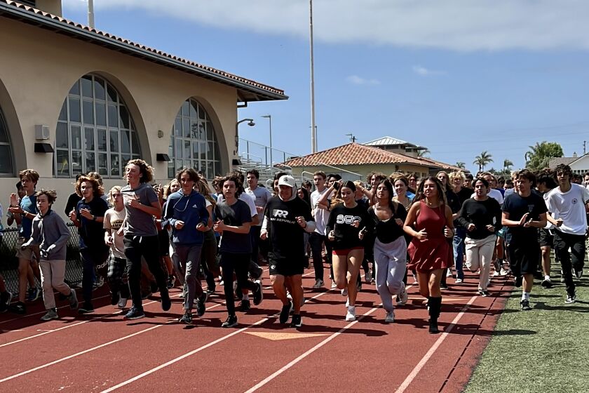 La Jolla High teacher and coach Tom Atwell (front, in white hat) completes his 400th lap (and 100th mile) June 2