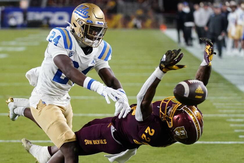 UCLA defensive back Jaylin Davies (24) shoves Arizona State wide receiver Bryan Thompson.