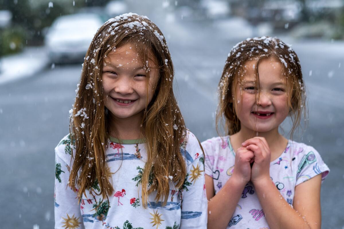 Two girls grin as snow collects in their hair