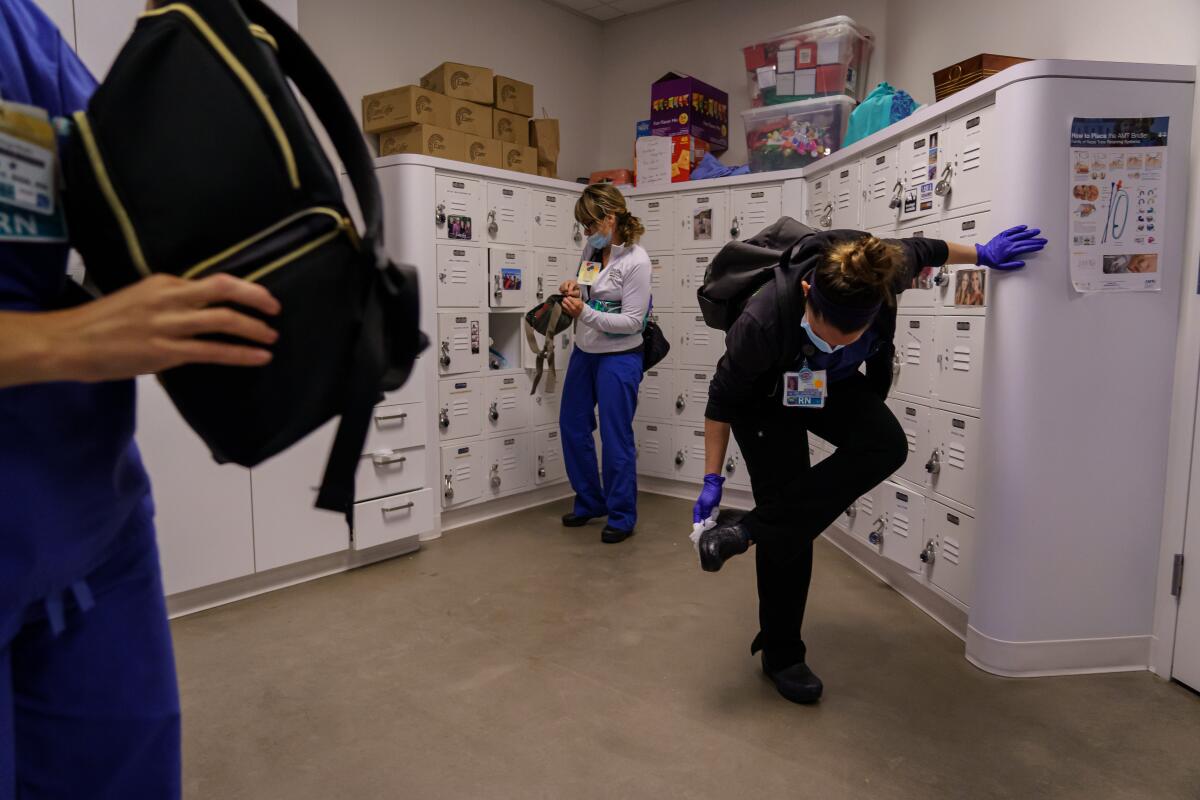 After her work shift is over, registered nurse Erin Jenkins packs up and disinfect her shoes, belongings and other areas that might come in contact with any surfaces at the locker room at a San Diego hospital on April 18.