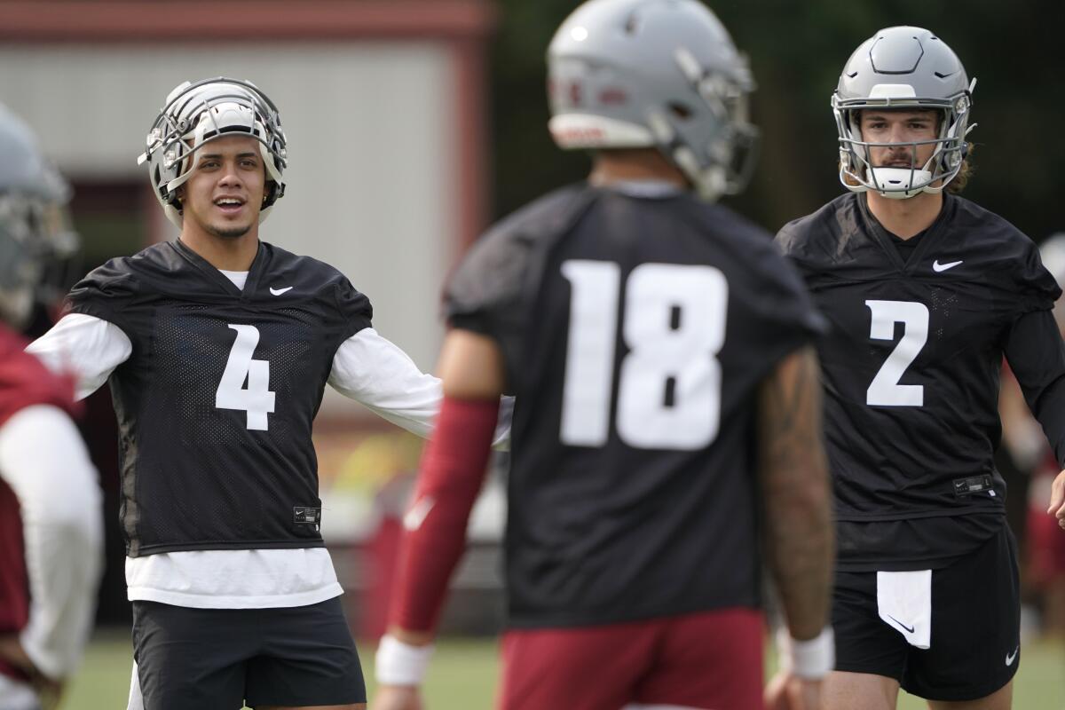 FILE - Washington State quarterbacks Jayden de Laura (4), Cammon Cooper (2), and Jarrett Guarantano (18) stand together on the first day of NCAA college football practice in Pullman, Wash., in this Friday, Aug. 6, 2021, file photo. WSU head coach Nick Rolovich would like for attention going into the 2021 season to be focused on players on the field, but he is getting just as much attention around his decision not to receive a COVID-19 vaccination.(AP Photo/Ted S. Warren, File)