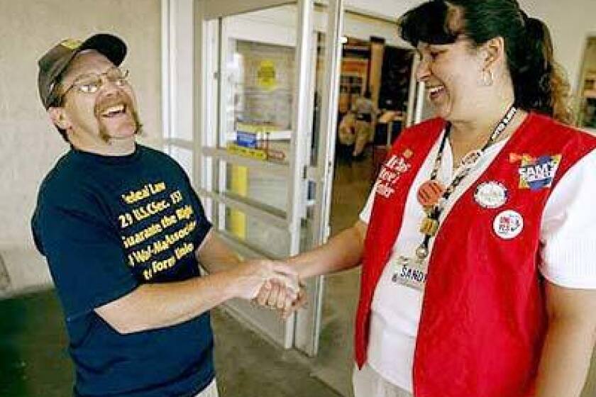 Wal-Mart employee Larry Allen, left, shakes hands with Sam's Club employee Sandy Williams at a Sam's Club in Las Vegas. Each is trying to unionize their stores.