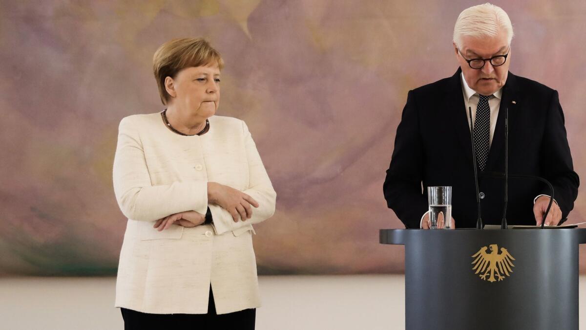German Chancellor Angela Merkel attends a ceremony where the country's new justice minister was given her certificate of appointment by German President Frank-Walter Steinmeier, right, at the presidential Bellevue Palace in Berlin on Thursday.