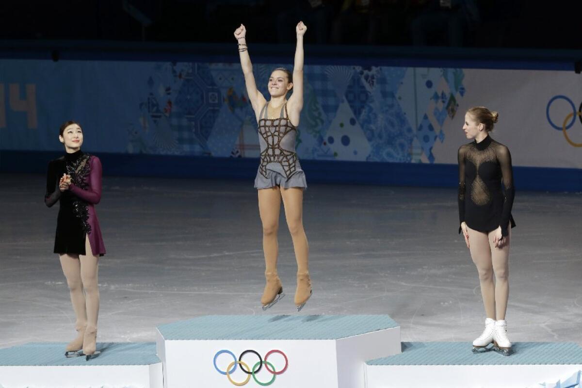 Adelina Sotnikova, center, Yuna Kim, left, and Carolina Kostner stand on the podium during the flower ceremony for the women's free skate figure skating finals at the Sochi Olympics.