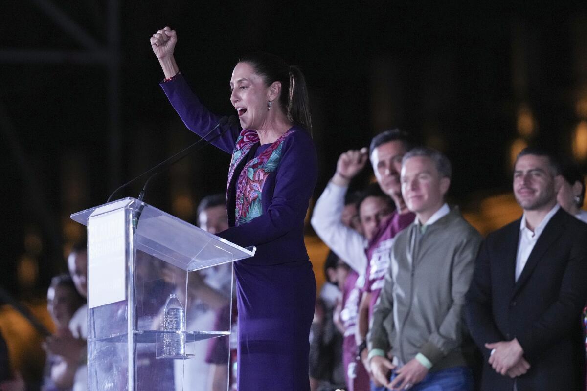 Mexican President-elect Claudia Sheinbaum stands behind a lectern and raises a fist while speaking to supporters.
