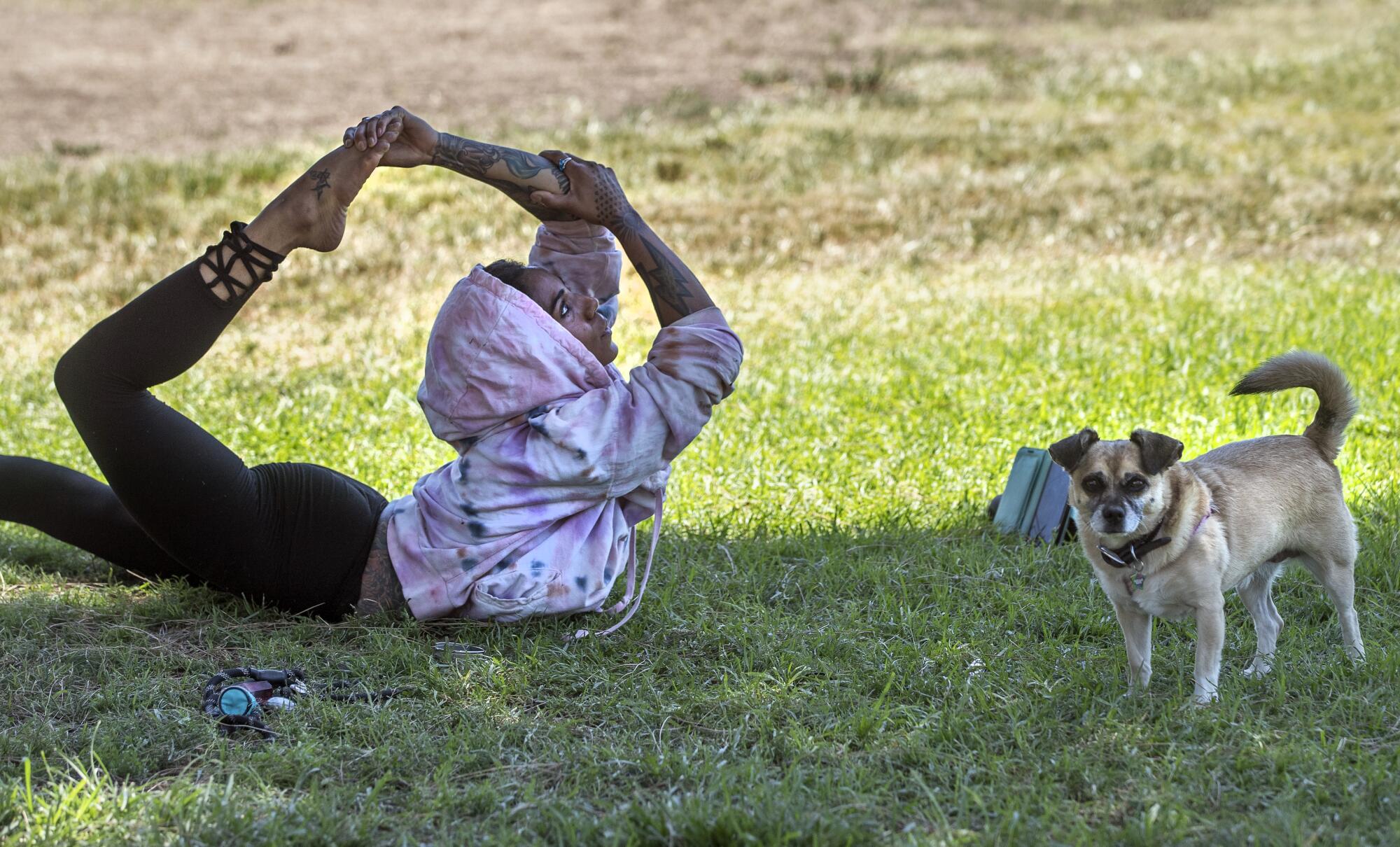 Aika Jh of Sherman Oaks stretches in the shade next to her dog Bridgette Barko.